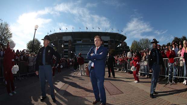 Nick Saban with arms cross in front of Bryant-Denny Stadium